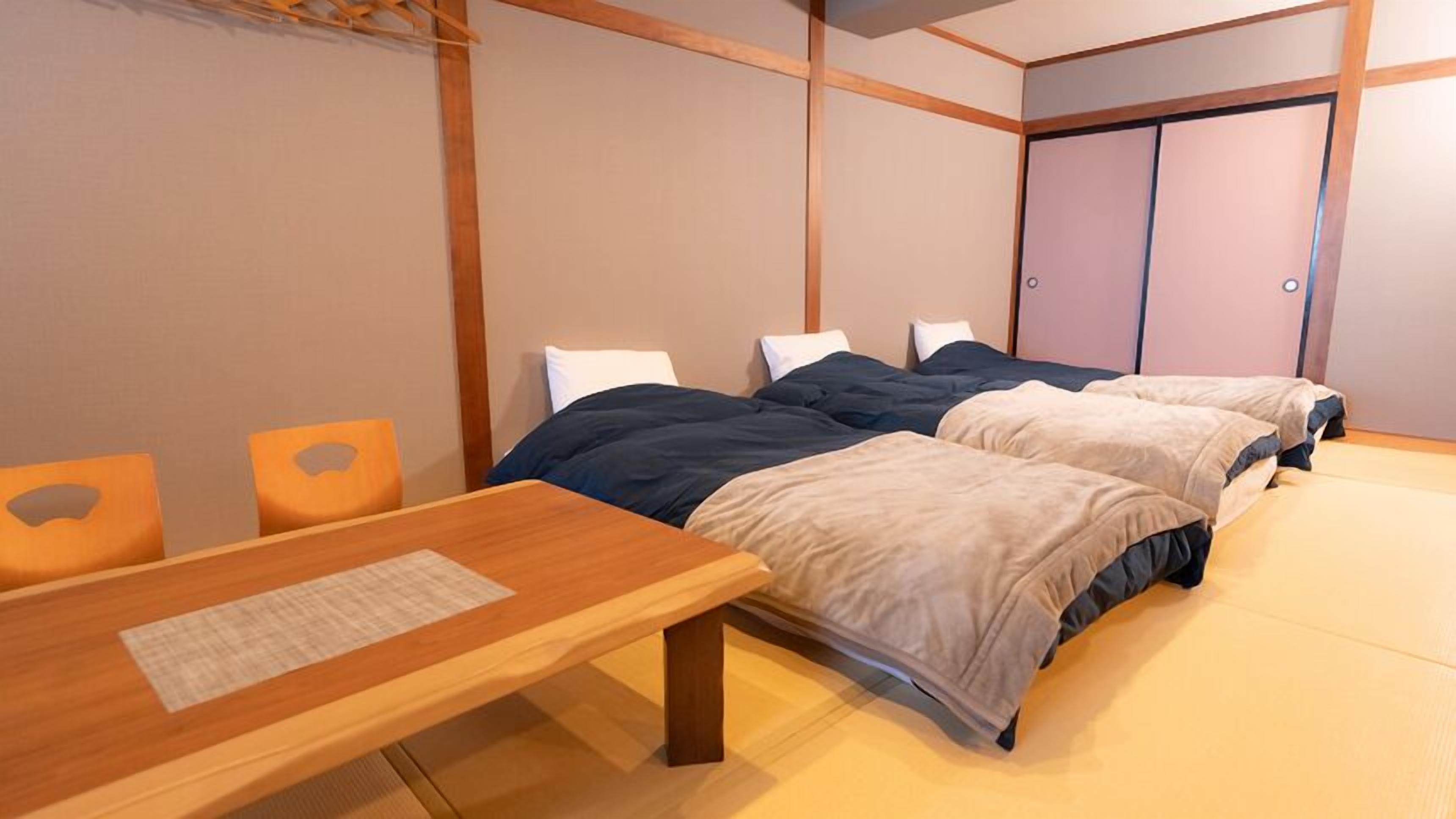 Una habitación con dos camas, una mesa de madera y un armario.