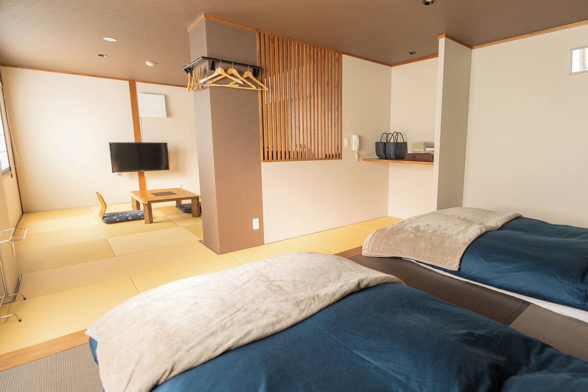 A room with two beds, a TV, a desk, and a chair.