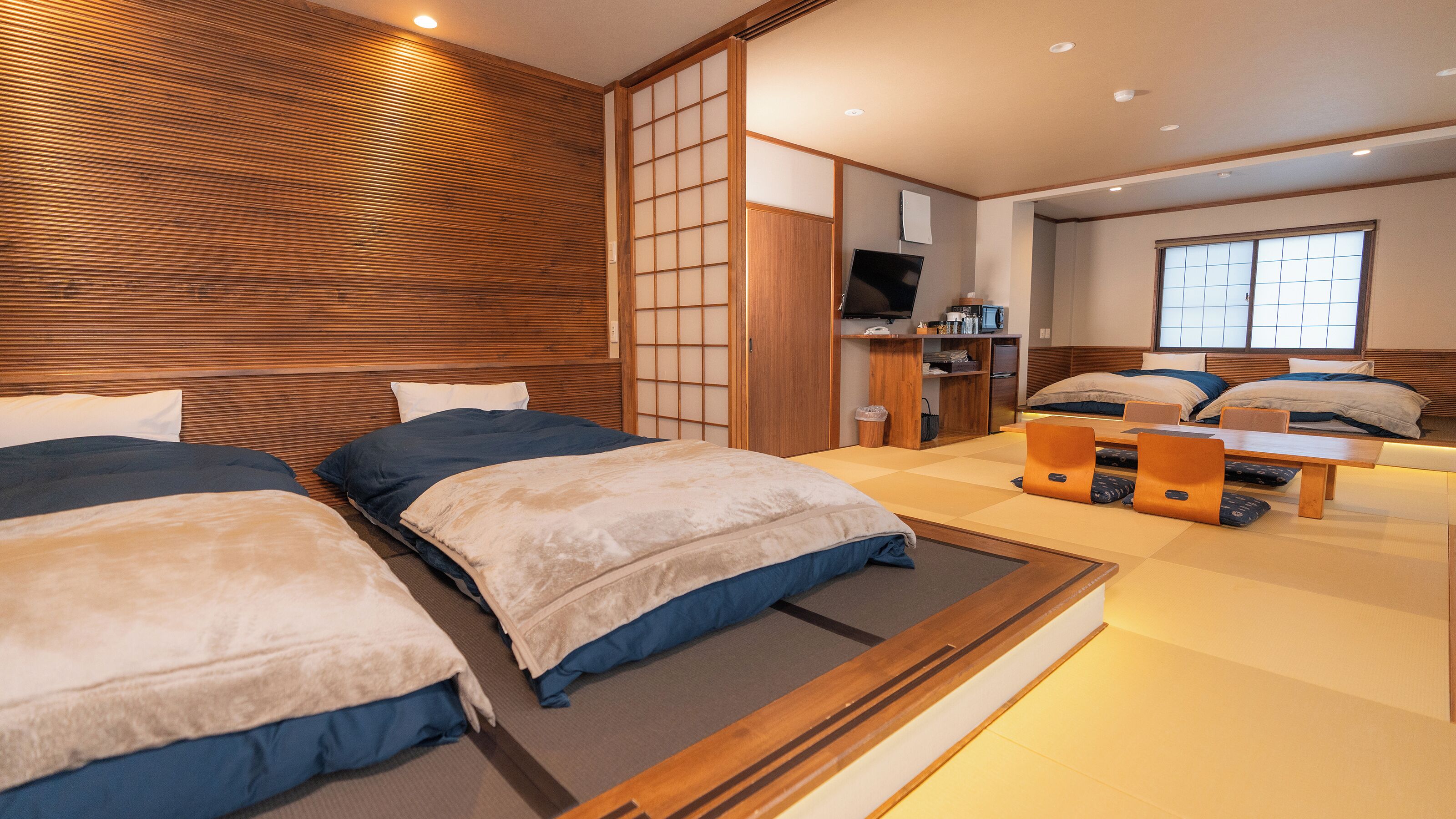 Habitación de hotel con dos camas, cabecera de madera, televisor, escritorio y ventana con vista.