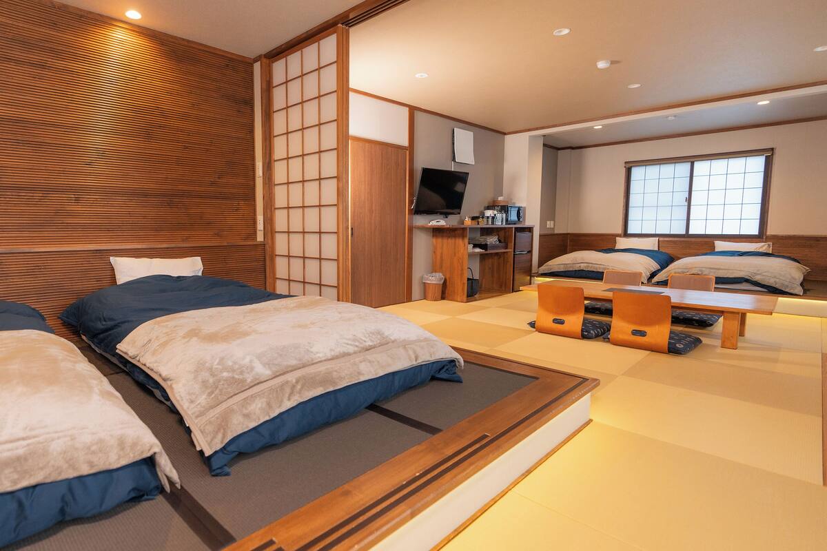 A hotel room with two beds, a wooden headboard, a TV, a desk, and a window with a view.