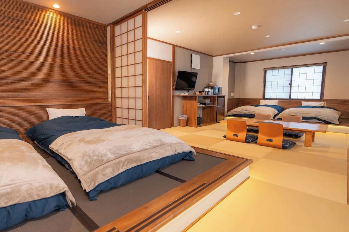 A hotel room with two beds, a wooden headboard, a TV, a desk, and a window with a view.