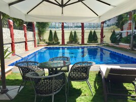Una piscina al aire libre, sillones reclinables de piscina