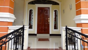 A grand entrance with a wooden door, a tiled floor, and a black wrought iron railing. - The Executive Villa Inn & Suites (Davao)