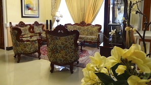 A room with two ornate armchairs, a sofa, a red patterned rug, and a large window with yellow curtains. - The Executive Villa Inn & Suites (Davao)