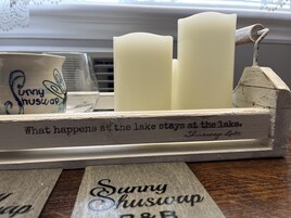 Un letrero de madera con el texto 'Sunny Shuswap B&B' y un candelabro con velas.