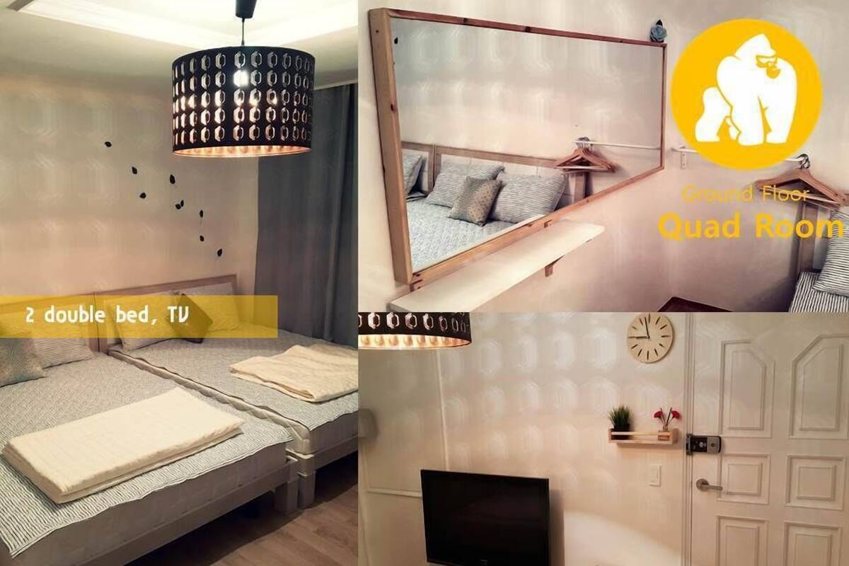 Ein Mehrbettzimmer mit zwei Doppelbetten, einem Fernseher und einem Spiegel.