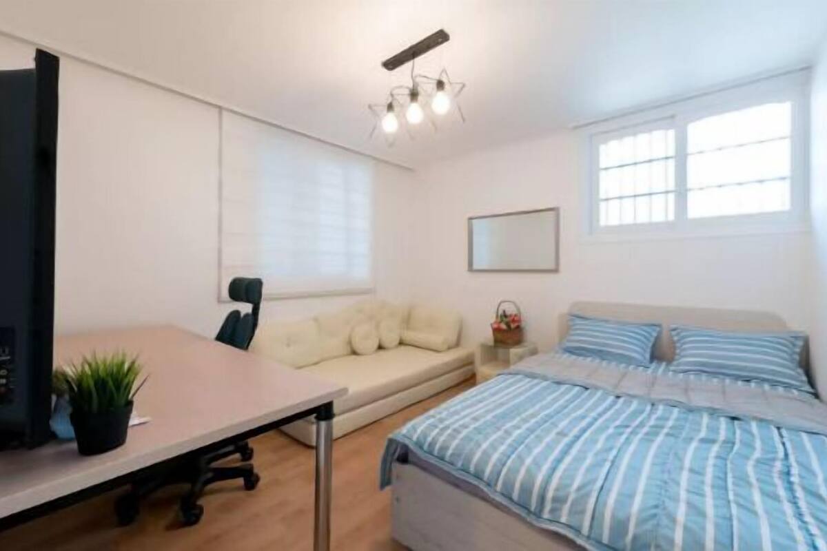 Ein Schlafzimmer mit Bett, Sofa, Schreibtisch und Sessel.