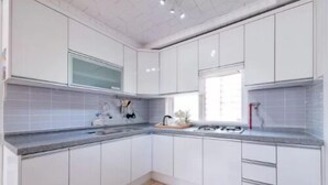Une cuisine moderne avec des meubles blancs, un plan de travail en granit et une fenêtre qui laisse entrer la lumière naturelle.