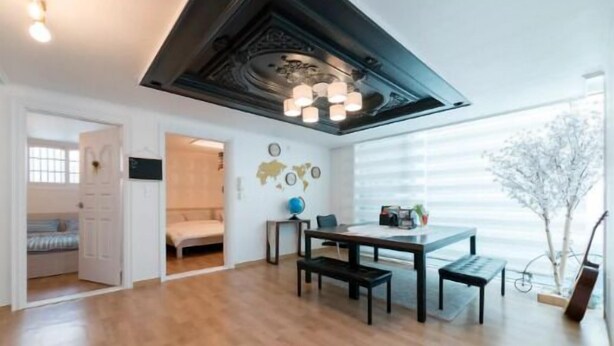 Une pièce avec un plancher en bois, une table à manger avec des bancs, un globe terrestre et une guitare appuyée contre le mur.