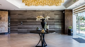 A modern lobby with a round table, a vase with flowers, and a unique ceiling light fixture. - CSuites at 8 Newtown Residences (Lapu-Lapu)