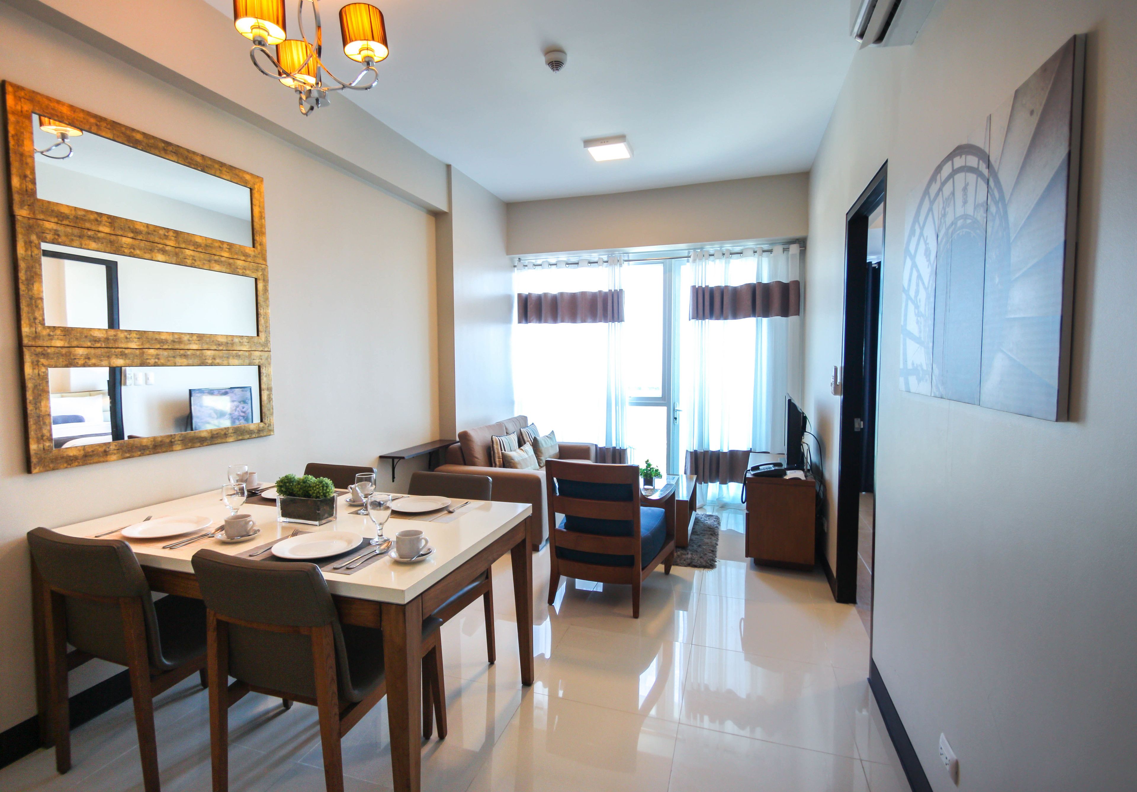 A modern living room with a dining area, a large mirror, and a television.