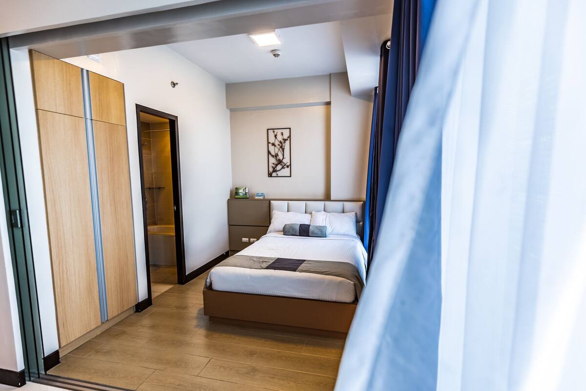 Une chambre d’hôtel moderne dotée d’un grand lit, d’une armoire, d’une table de chevet et d’une œuvre d’art accrochée au mur.