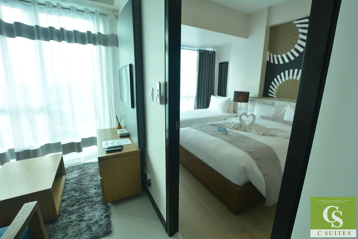 Une chambre d’hôtel avec un lit, une table de chevet, une lampe et une vue sur l’extérieur.