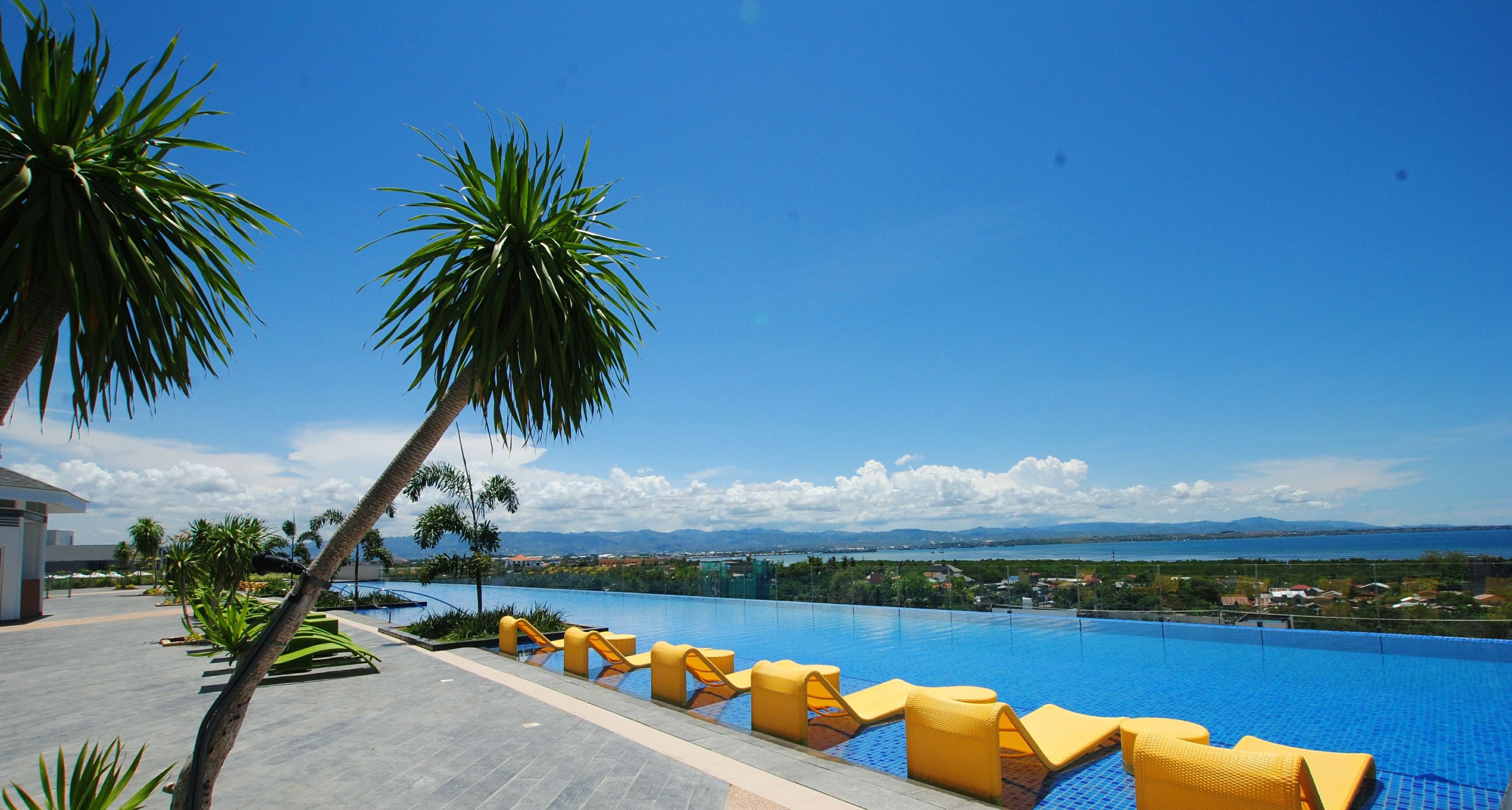 Una piscina al aire libre, sombrillas, sillones reclinables de piscina