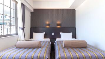 Habitación de hotel con dos camas, un ventanal grande y vista a la ciudad.