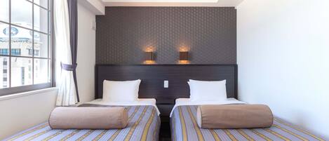 A hotel room with two beds, a large window, and a city view.