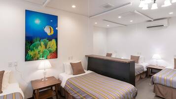 Habitación de hotel con cama, mesitas de noche, escritorio, silla, televisor y un cuadro de una escena nocturna con luna y estrellas.