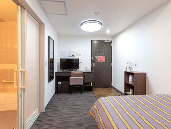 A hotel room with a bed, a desk with a TV, a shower, and a door with a sign. - Hotel KOZA (Okinawa)