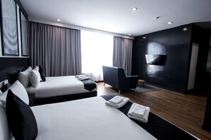 A modern hotel room with two beds, a flat-screen TV, and a large window with curtains. - Bloommaze Boutique Hotel (Puchong)