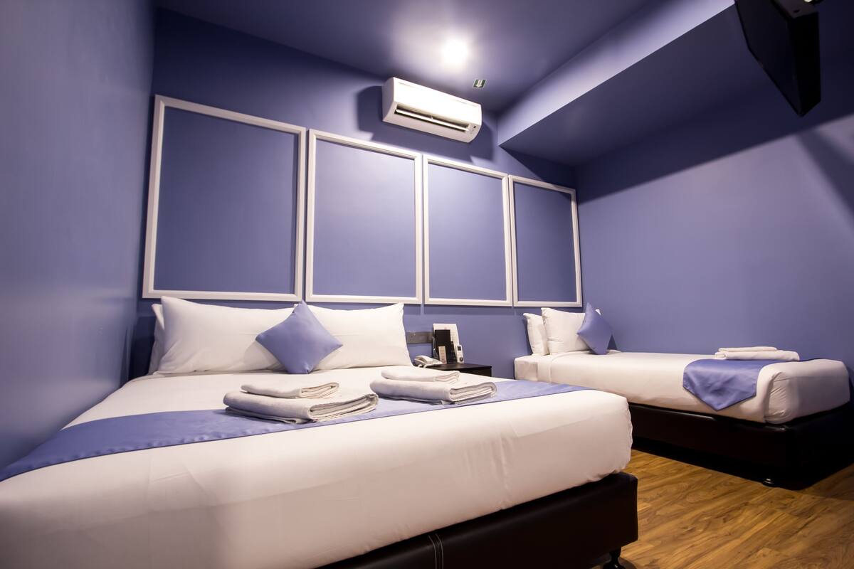 A hotel room with two beds, a large window, and an air conditioning unit.