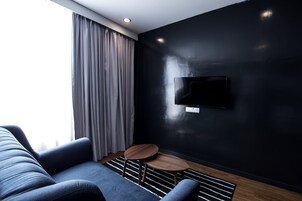 A modern living room with a dark wall, a mounted TV, a sofa, and a small round table.