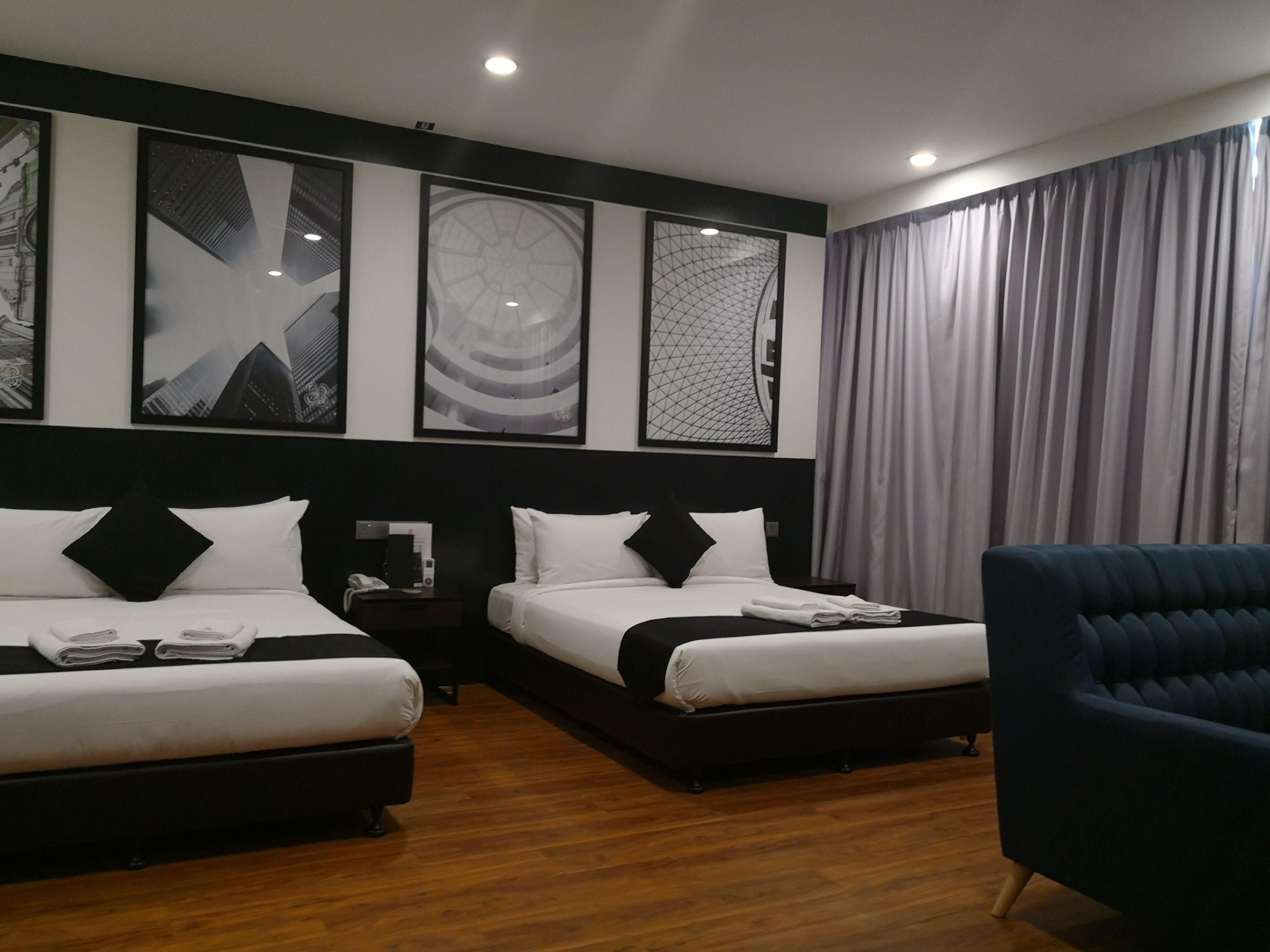 A hotel room with two beds, a nightstand, a chair, and artwork on the wall.