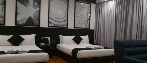 A hotel room with two beds, a nightstand, a chair, and artwork on the wall.