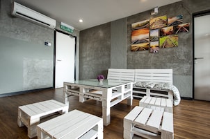 A room with a bed, a glass-top table, and white wooden benches.