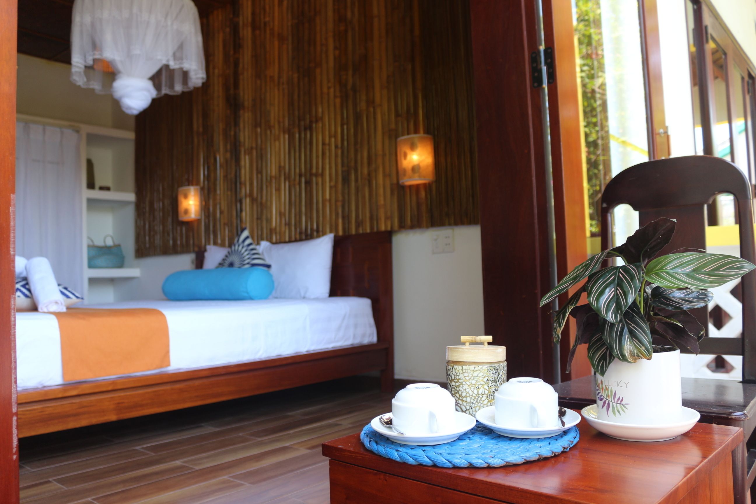 A bedroom with a bed, bedside table, and a window with a view of greenery.