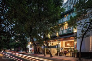 A traditional building with multiple stories, a sign for 'Hanoian Central Hotel & Spa,' and a street with light trails indicating traffic.