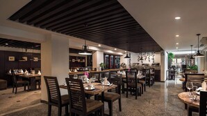 A restaurant with wooden tables and chairs, a bar area, and pendant lighting. - Hanoian Central Hotel & Spa (Hanoi)