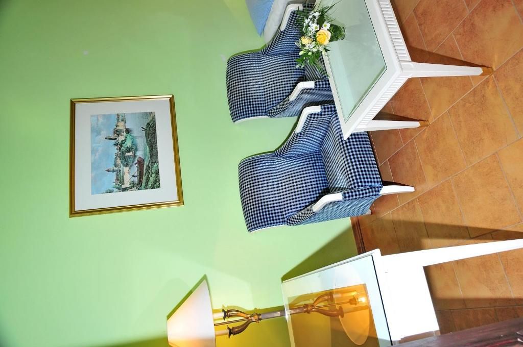 A dining area with a table and chairs, a framed picture on the wall, and a lamp.