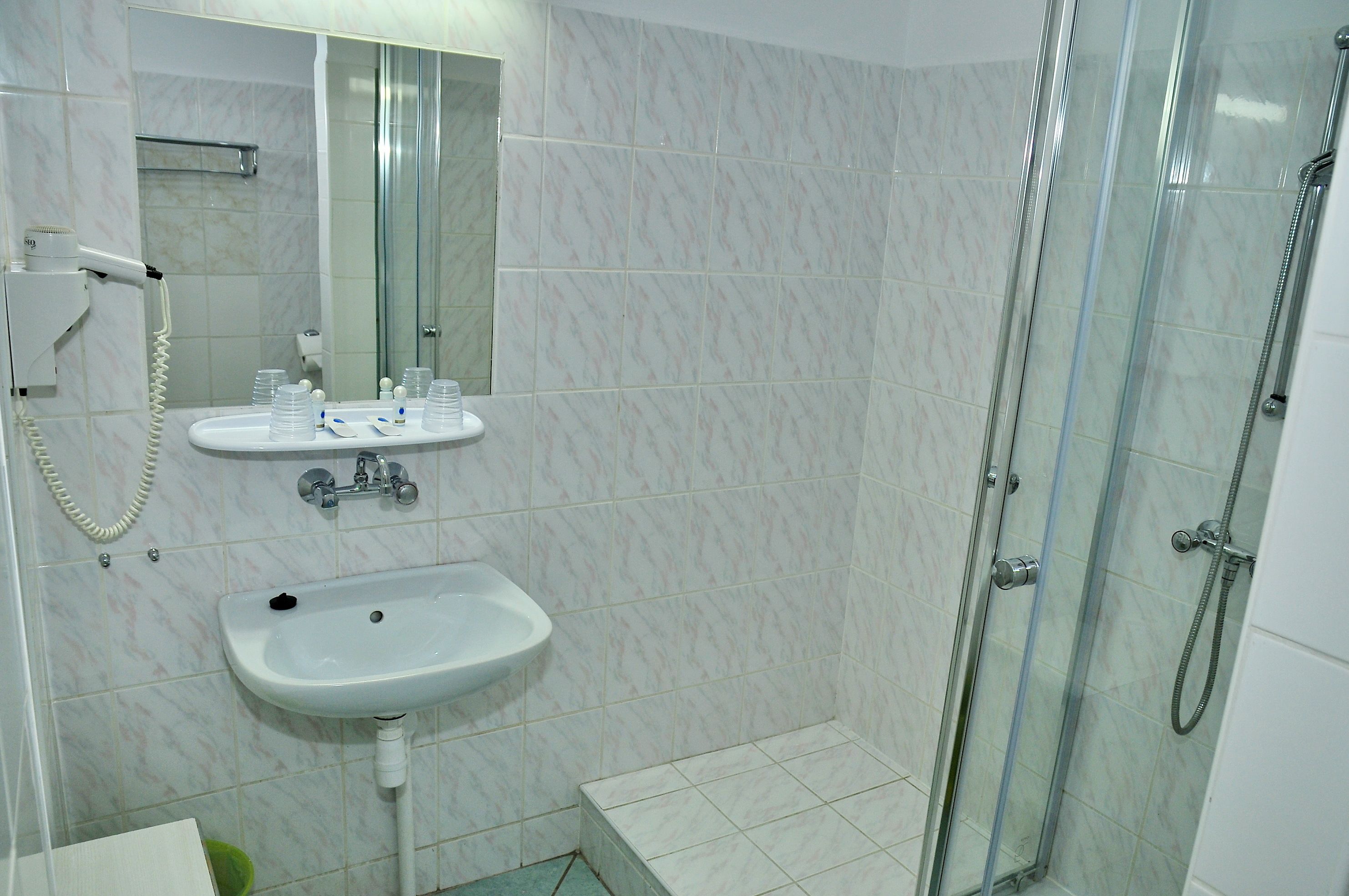 Un bagno con doccia vetrata, lavabo e specchio.