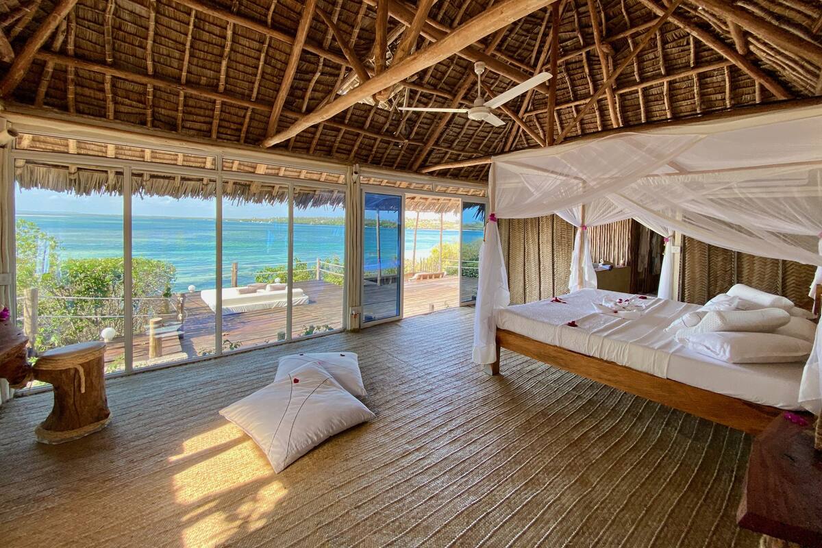 Una habitación con cama, ventilador de techo y vista al océano.