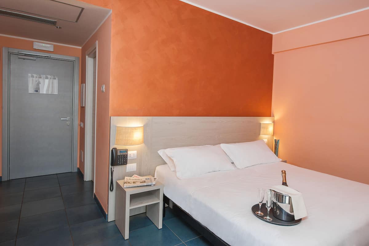 Ein Hotelzimmer mit einem Bett, einem Nachttisch und einem Beistelltisch mit einer Lampe.