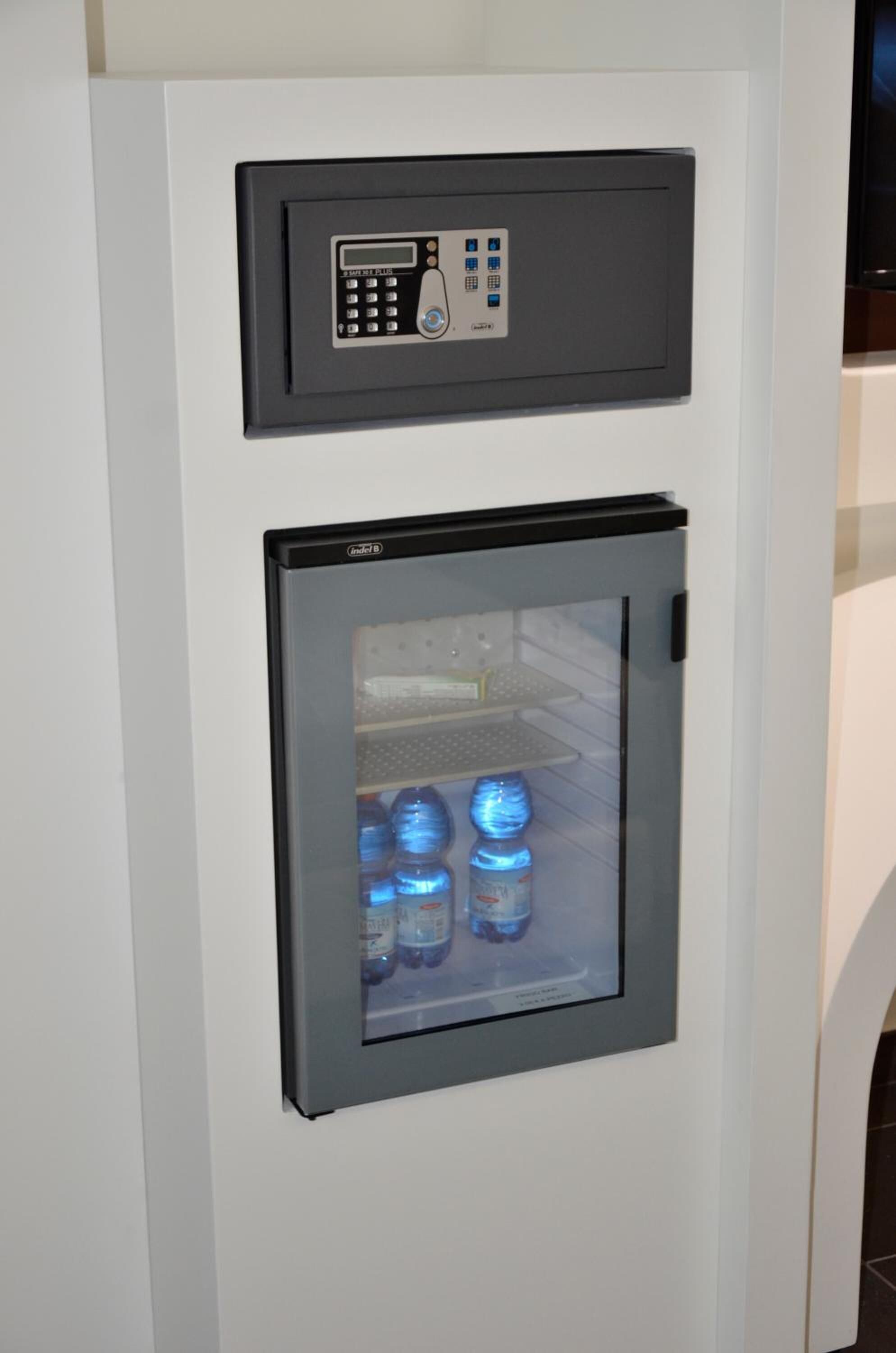 A compact refrigerator with a digital control panel and a glass door, containing several water bottles.