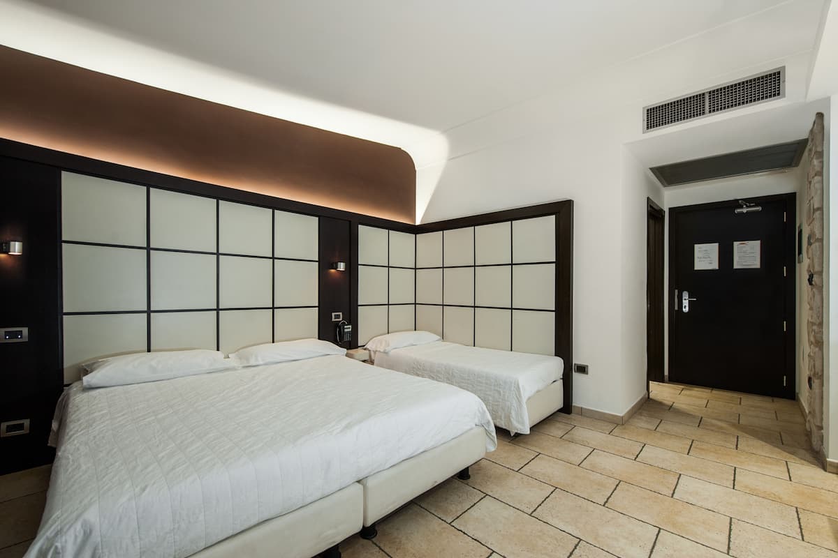 A hotel room with two beds, a modern design, and a stone accent wall.