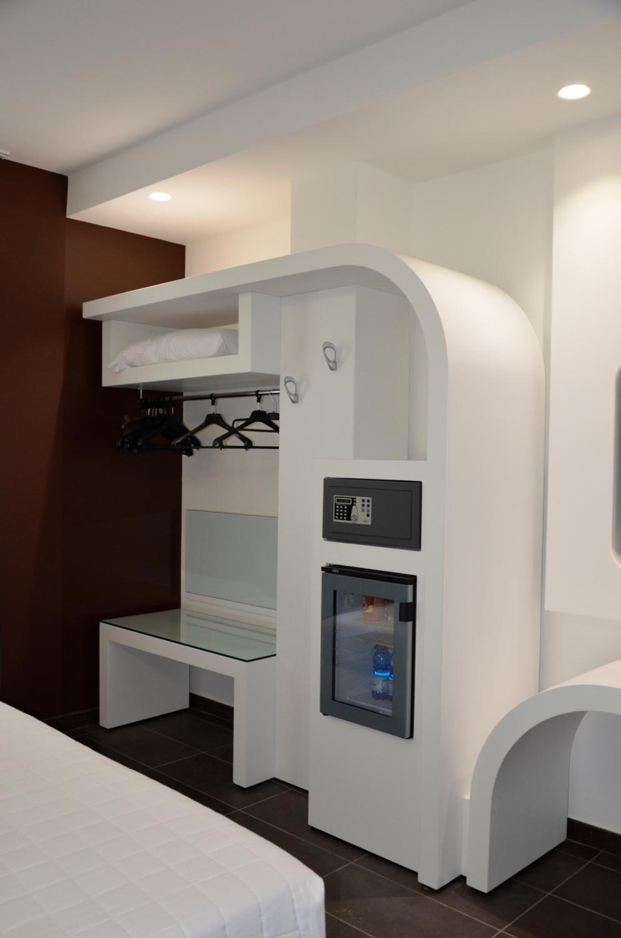 Una habitación de hotel moderna con una cama individual, un minibar y un pequeño rincón de estar.