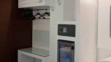 Una habitación de hotel moderna con una cama individual, un minibar y un pequeño rincón de estar.