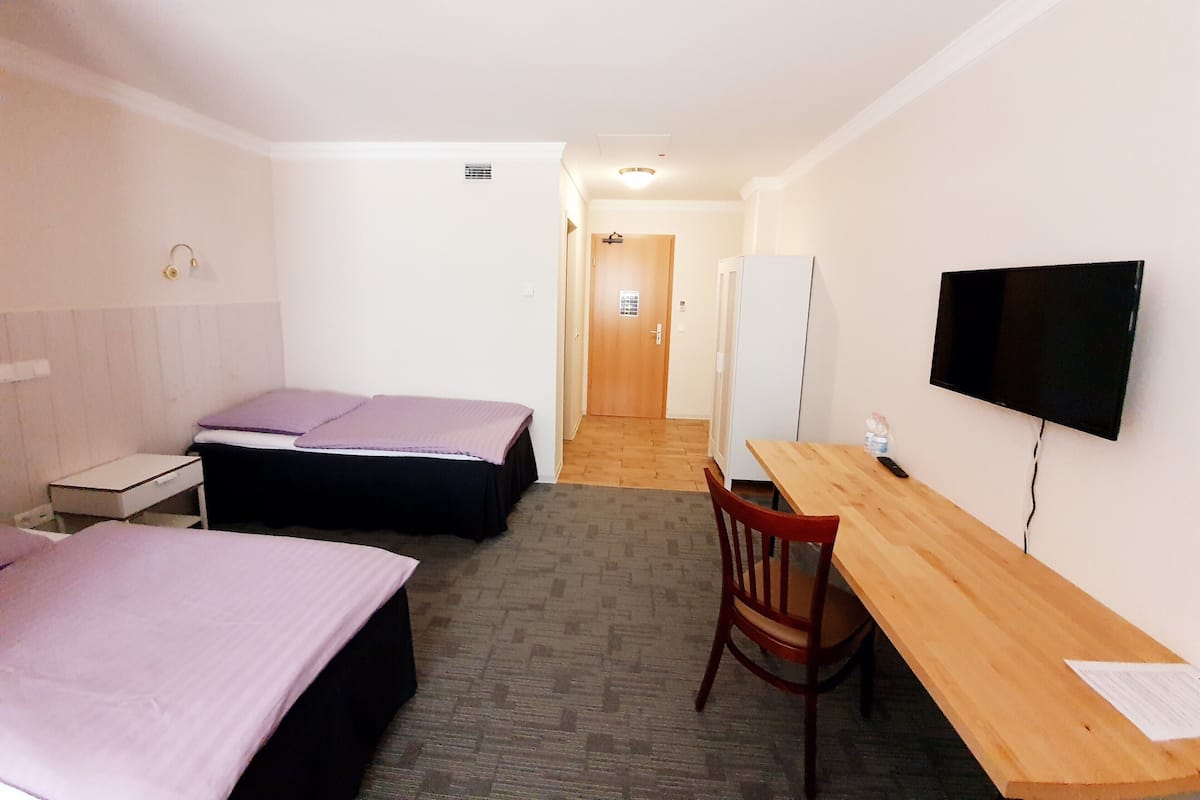 Une chambre d’hôtel avec deux lits, un bureau, une chaise, une télévision et un réfrigérateur.
