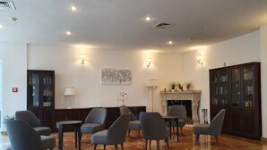 A spacious lobby with a fireplace, seating area, and a large bookcase. - Hotel Pause (Hofheim am Taunus)