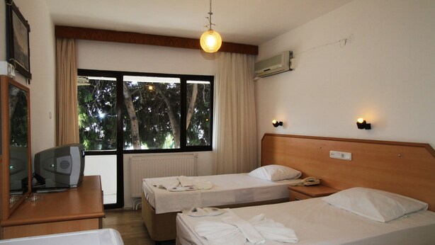 A hotel room with two beds, a desk, a chair, a television, and a window with curtains.