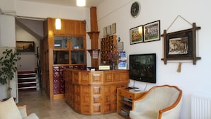A reception area with a wooden desk, a chair, a TV, and framed pictures on the wall.