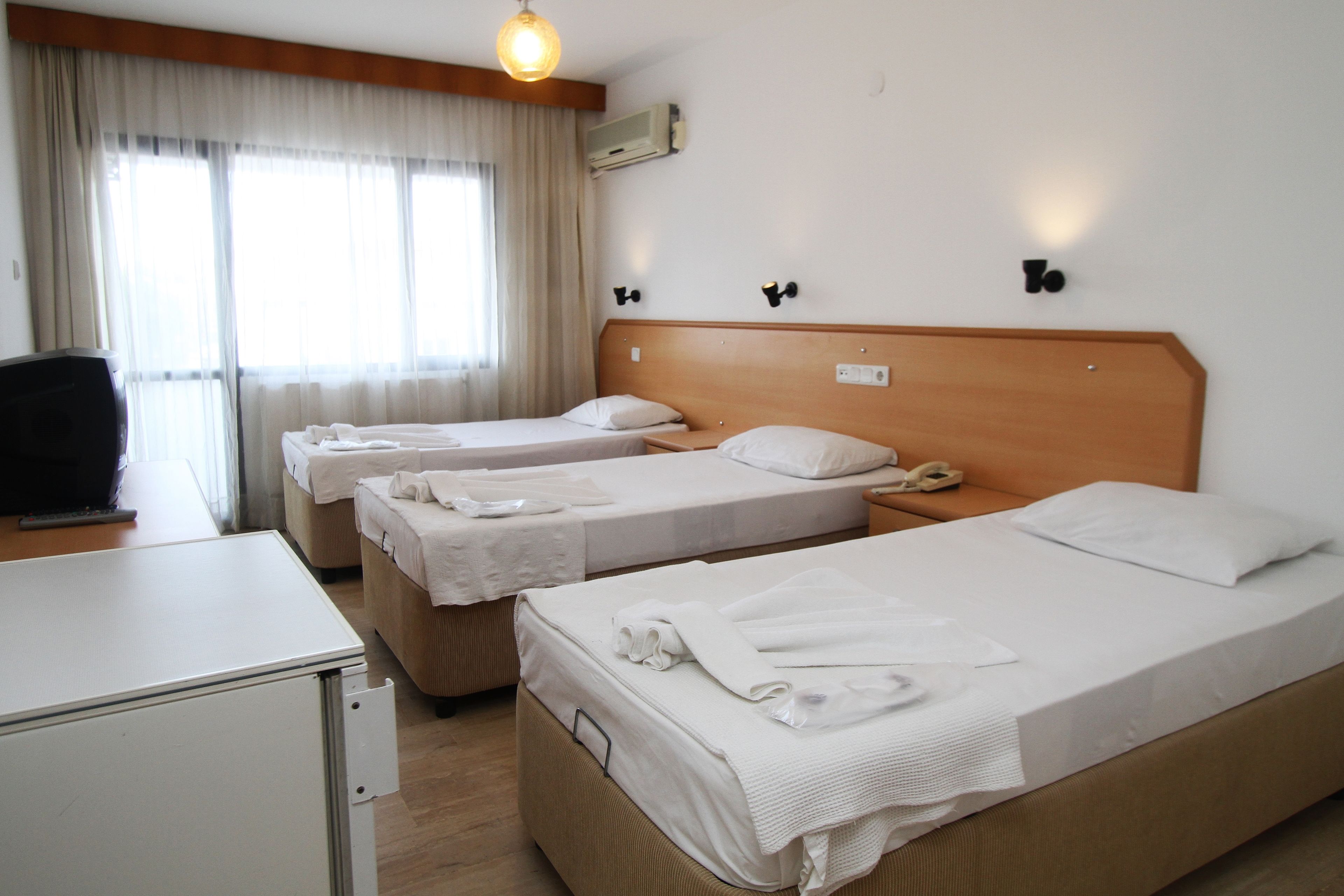 A hotel room with three beds, a desk, and a television.