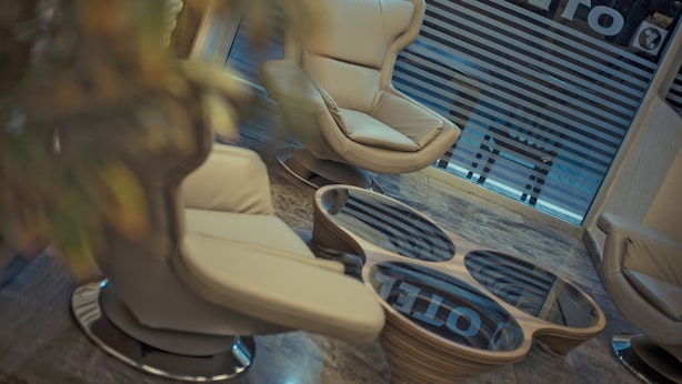A modern hotel lobby with a large window, a reception desk, and a seating area with a massage chair and foot spa. - Yayla Hotel (Izmir)