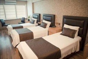 Ein Hotelzimmer mit zwei Einzelbetten, einem Schreibtisch und einem Stuhl.