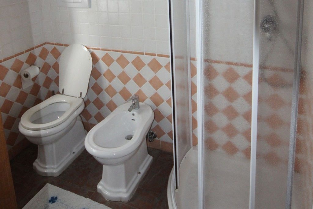 A bathroom with two toilets, a bidet, and a shower.