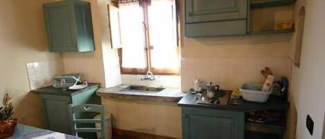 A compact kitchen with a window, a sink, and a small dining area.