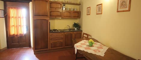 A kitchen with wooden cabinets, a sink, and a table with a lace tablecloth.