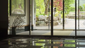 Ein modernes Interieur mit einem Schachbrettmuster-Bodenbelag, einer Topfpflanze und Blick auf einen Garten durch Glastüren.